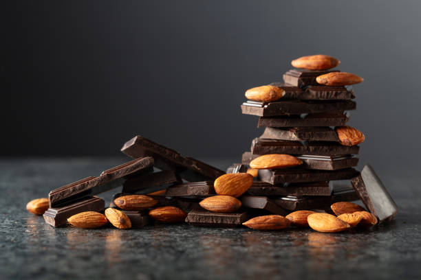 Broken dark chocolate bar with almond on a black background. Copy space. Broken dark chocolate bar with almond on a black background. Copy space.