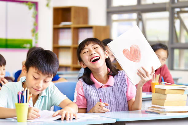 happy and lovely asian elementary school girl showing a drawing and laughing. happy and lovely asian elementary school girl showing a drawing and laughing.